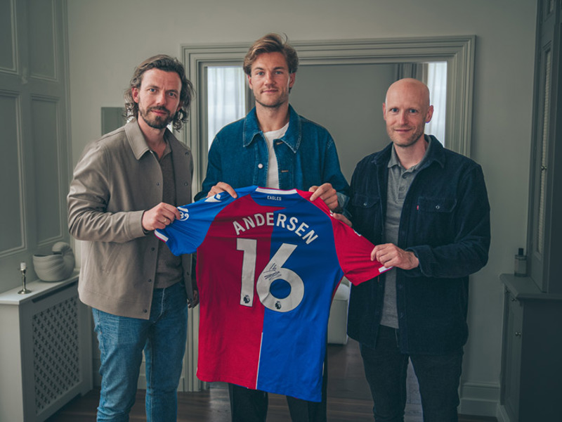 Joachim Andersen holds a signed Crystal Palace shirt flanked by RareWine Representatives